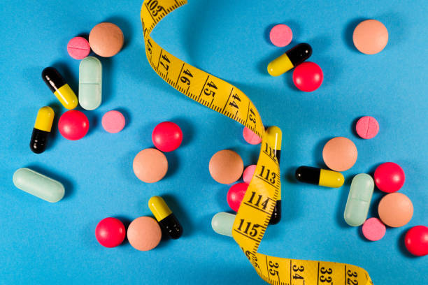 Yellow tape measure with a variety of weight loss medication on blue background. semaglutide weight loss medications