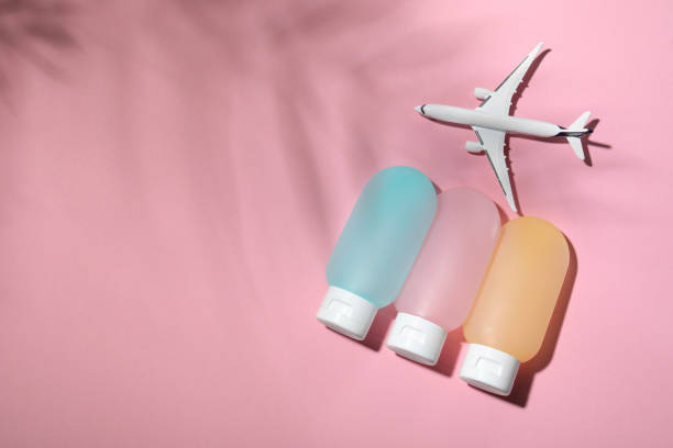 Cosmetic travel kit and toy plane on pink background, travel skincare