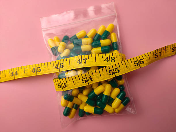 maintain weight after Semaglutide Closeup of a medicine pill package with measuring tape on a pink background.